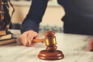 A person is holding a gavel on the table